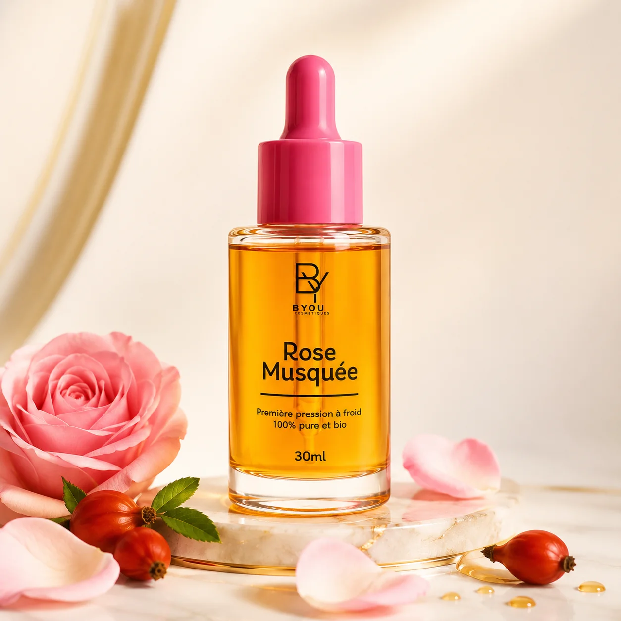 Huile de rose musquée bio Byou posée sur marbre clair avec rose et baies d'églantier — soin visage anti-âge naturel