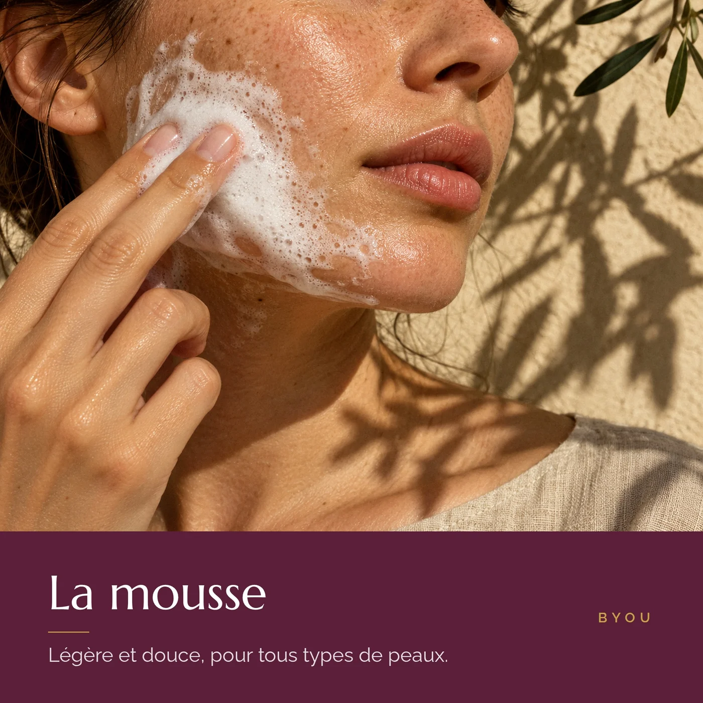 Visage de femme avec la mousse nettoyante légère appliquée sur la joue