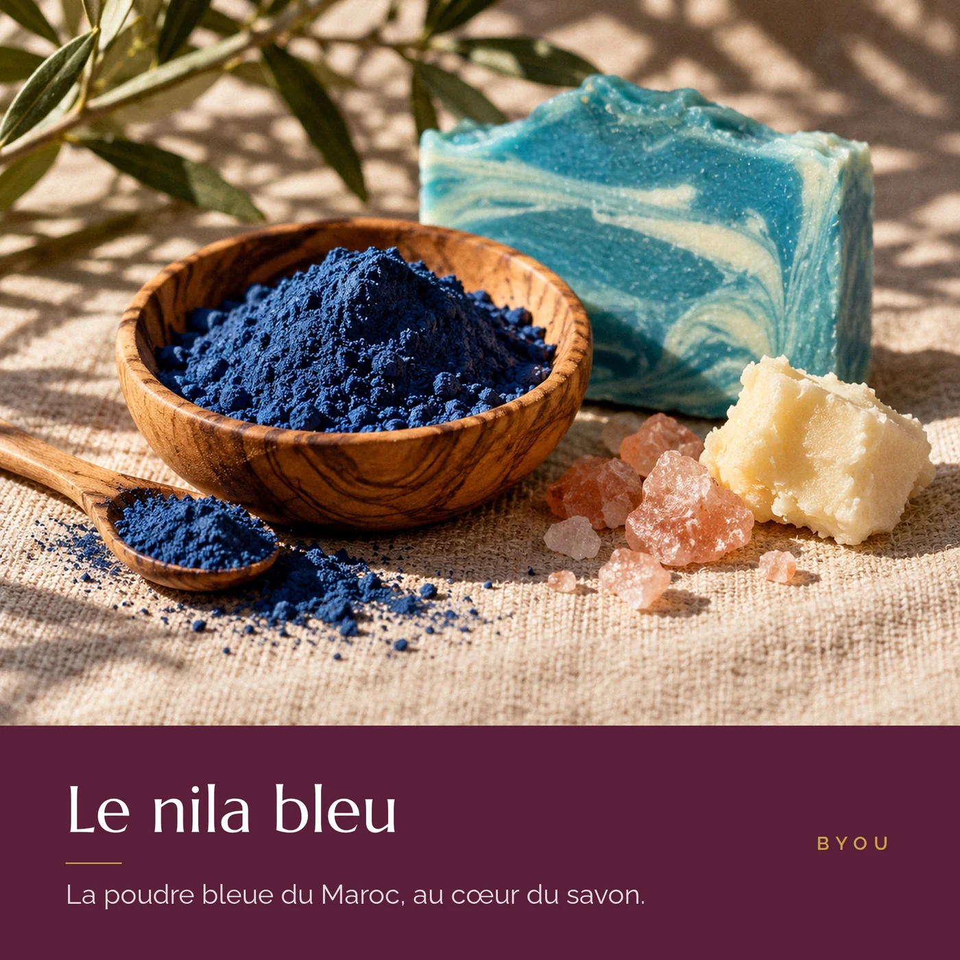 Poudre de nila bleu dans un bol en bois d’olivier à côté du savon au nila